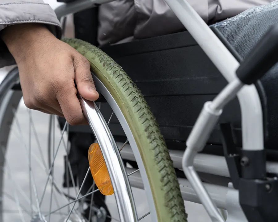 Hand am Greifreifen eines Rollstuhls